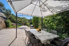 An outdoor patio with a table and chairs, a canopy, and a stone wall.