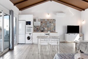Une cuisine moderne équipée d’un lave-linge, d’un coin repas avec des chaises, d’une télévision et d’un crédence décorée.