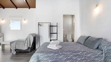 Une chambre moderne avec un grand lit, un banc, une échelle et une porte de salle de bain.