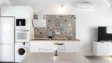 A modern kitchen with a washing machine, a microwave, and a built-in oven.