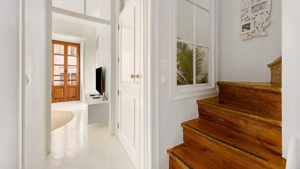 A staircase leading to a room with a television and a wooden door.