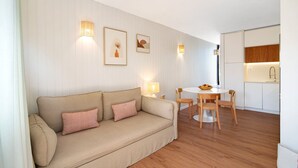 A modern living room with a beige sofa, a dining table with chairs, and a kitchen area in the background. - Villa "Casa da Gomeira" with Garden & Wi-Fi (Cabanas)