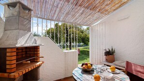 An outdoor patio with a brick oven, a round table with plates, bowls, and lemons, and a view of a garden. - Villa "Casa da Gomeira" with Garden & Wi-Fi (Cabanas)