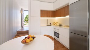 A modern kitchen with white cabinetry, a stainless steel Bosch refrigerator, and a fruit bowl on the table. - Villa "Casa da Gomeira" with Garden & Wi-Fi (Cabanas)