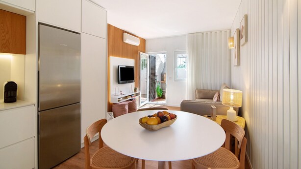 A modern kitchen with a stainless steel refrigerator, a dining area with a round table and wicker chairs, and a living area with a sofa and a lamp. - Villa "Casa da Gomeira" with Garden & Wi-Fi (Cabanas)