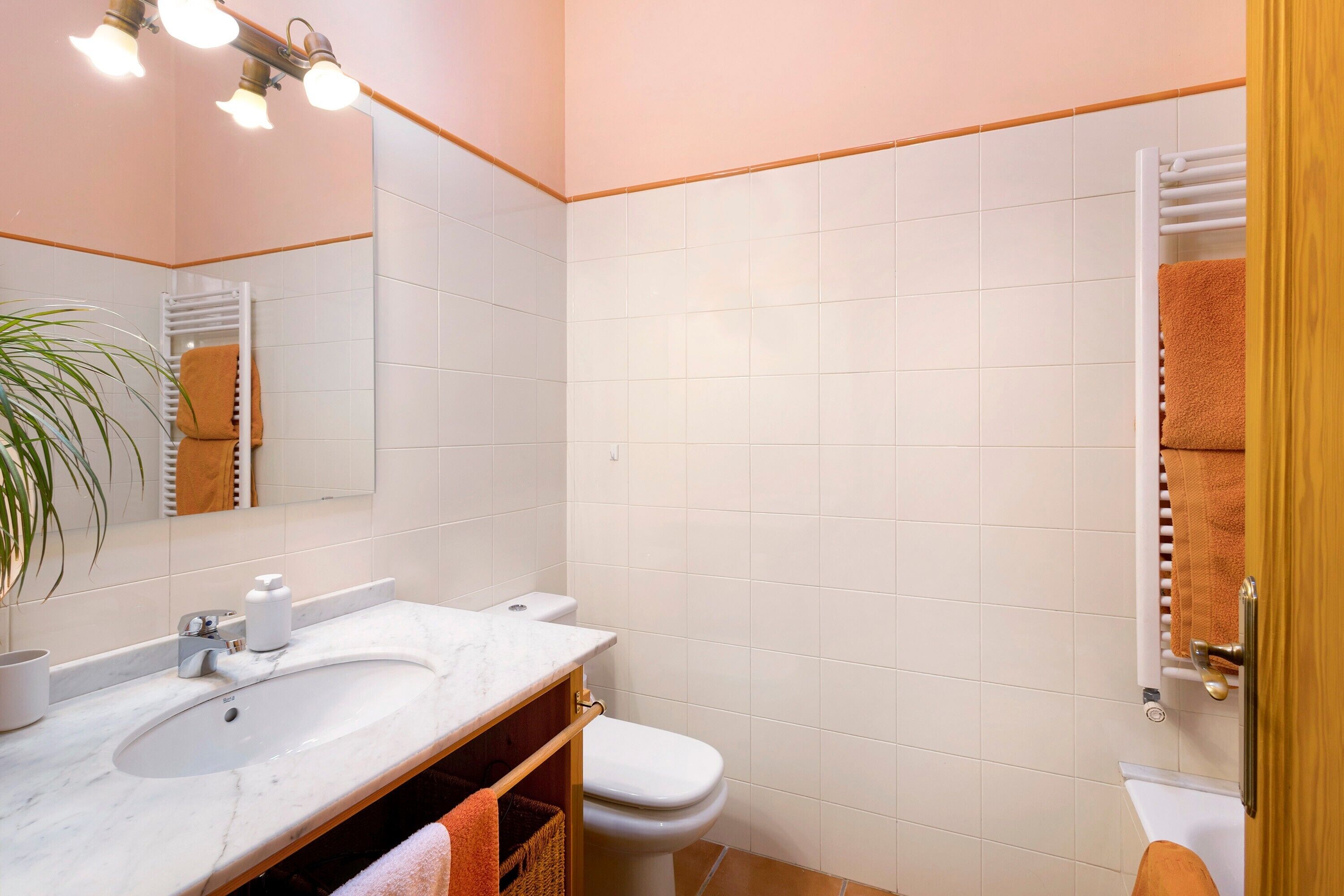 Un baño con lavamanos, espejo, toallero y retrete.
