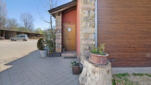 Un bâtiment en pierre avec une porte en bois, des plantes en pot et une porte de garage fermée.