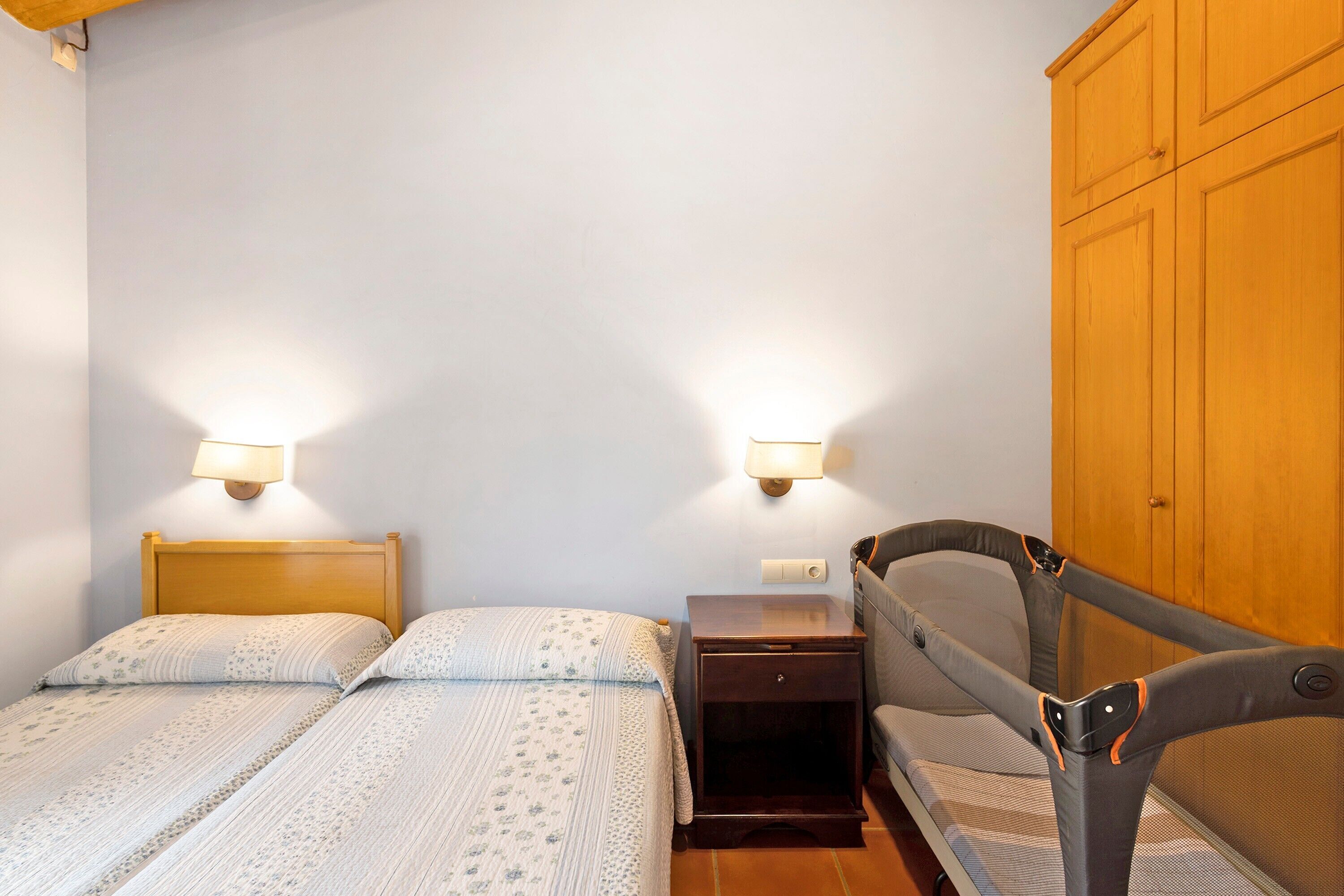 Ein Schlafzimmer mit Bett, Nachttisch und Kinderwagen.