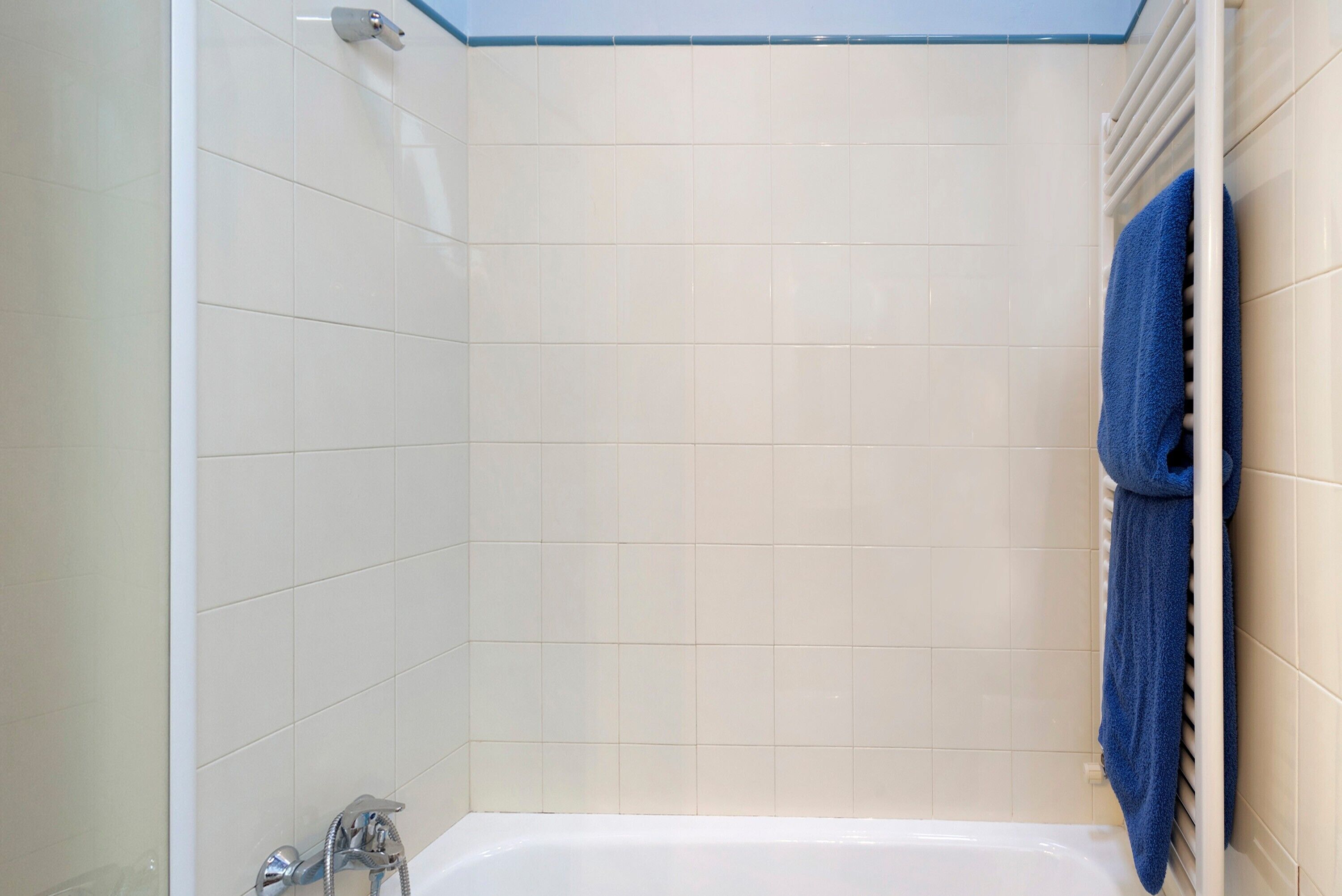 A bathroom with a shower, a bathtub, and a towel rack.