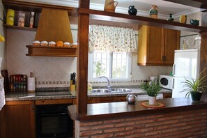A kitchen with a granite countertop, a sink, a microwave, and a brick wall.