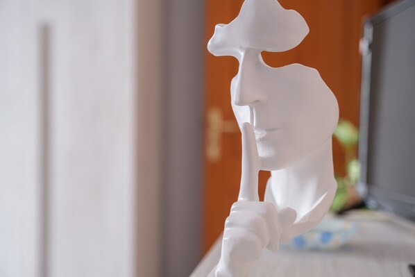 Una escultura blanca de una persona sosteniendo un sombrero.