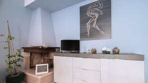 A modern living room with a fireplace, a flat-screen TV, a decorative painting, and a potted plant. - Vacation Home "La Casa Di Wioletta" with Sea View, Private Terrace & Wi-Fi (Barcellona pg)