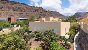 A residential area with buildings, a mountain, and a clear sky.