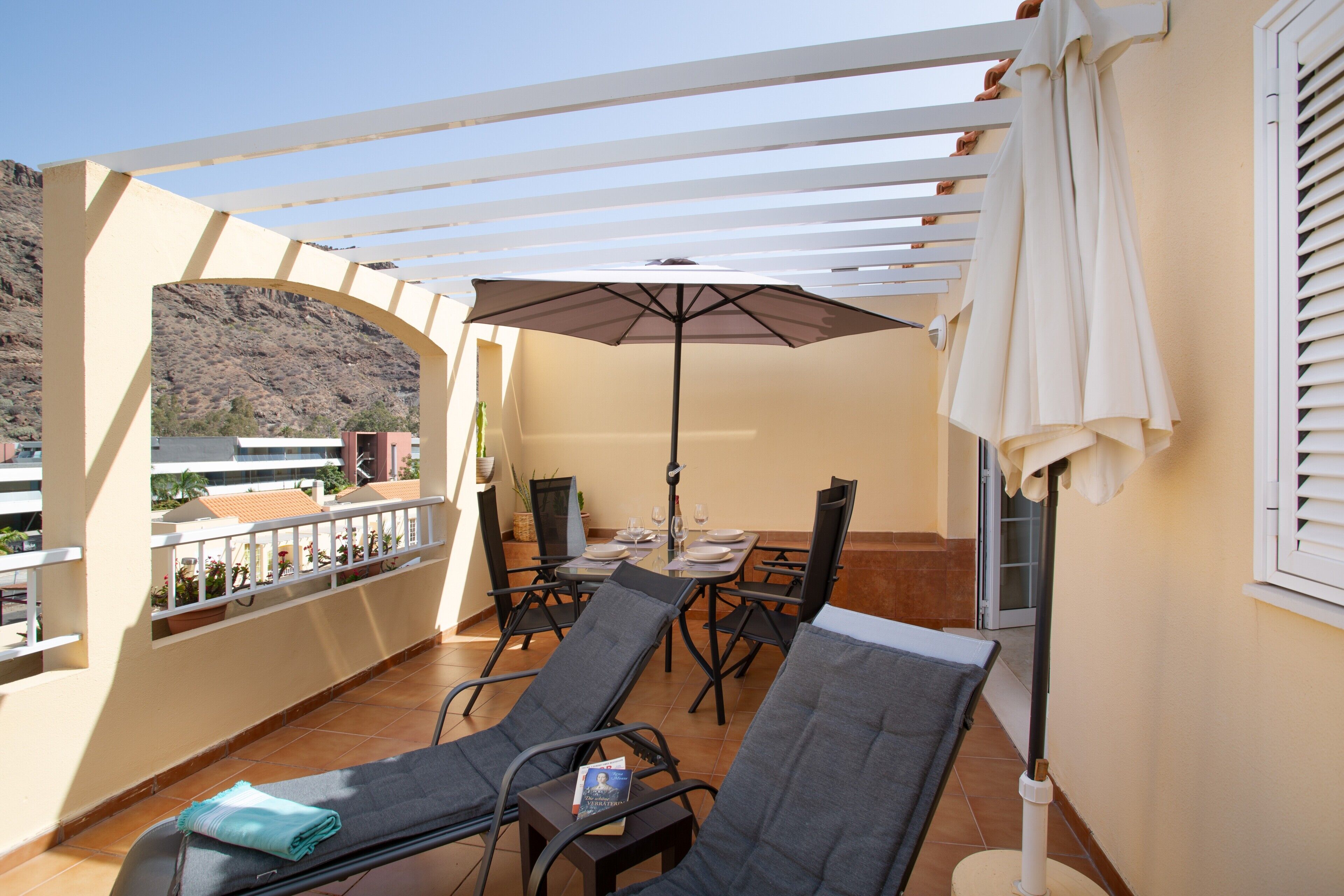 A balcony with a table, chairs, and an umbrella.
