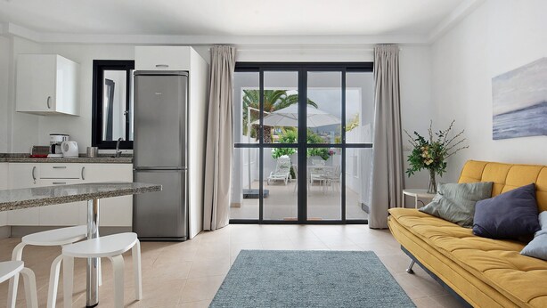A modern kitchen with a dining area, a sofa, and a view of the outdoors. - Vacation Home "Puerto Hills" with Mountain View, Shared Pool & Wi-Fi (Puerto de la cruz)