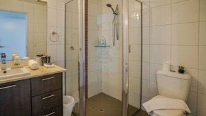 Ein Badezimmer mit einer gläsernen Duschkabine, Toilette und einem Waschtisch mit Spiegel.