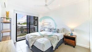 Ein modernes Schlafzimmer mit Bett, Nachttisch und Blick ins Freie.