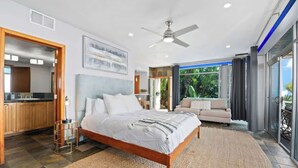 A bedroom with a large bed, a ceiling fan, and a view of the outdoors.