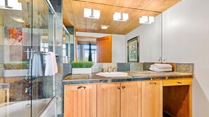A modern bathroom with a glass-enclosed shower, a wooden vanity with a sink, and a large mirror.