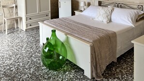 A bedroom with a bed, a wardrobe, a small table, a chair, and a green bottle on the floor. - Typical Salento romantic suite (Borgagne)