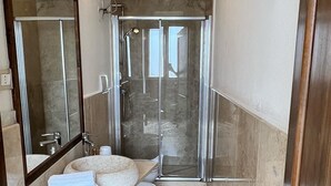 A bathroom with a glass shower enclosure, a sink with a mirror, and a towel rack. - Typical Salento romantic suite (Borgagne)