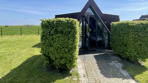 A modern building with a triangular roof and a glass entrance, surrounded by well-maintained hedges. - Hotelhuisjes Andijk (Andijk)
