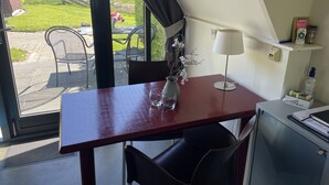 A room with a table, chairs, a lamp, a vase with flowers, and a view of the outdoors. - Hotelhuisjes Andijk (Andijk)
