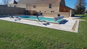 A house with a swimming pool, a wooden deck, and a grassy yard.