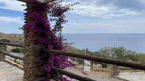 A stone pillar with purple flowers, a wooden railing, and a view of the sea.