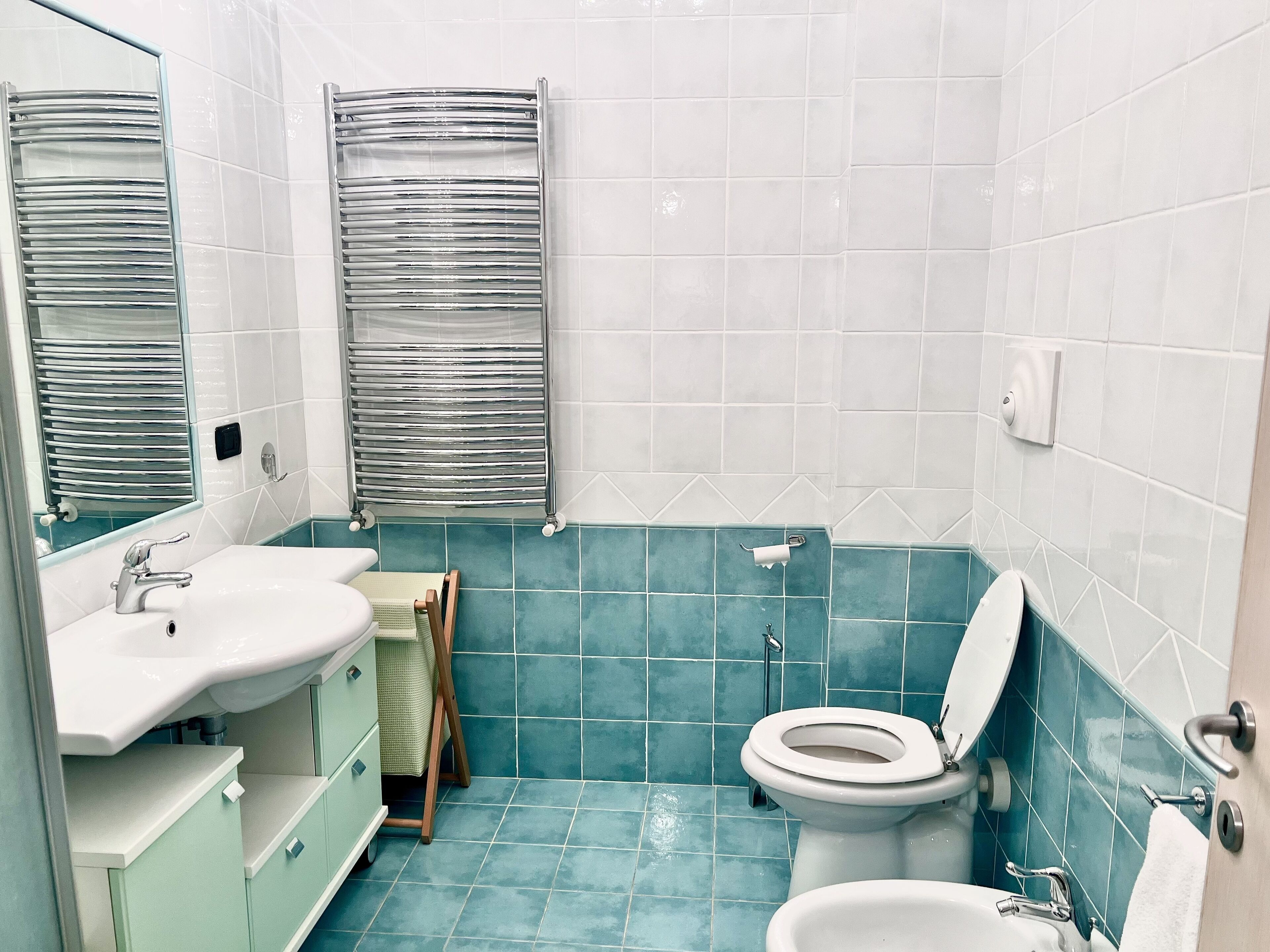 A bathroom with a sink, mirror, towel rack, toilet, and a shower area.