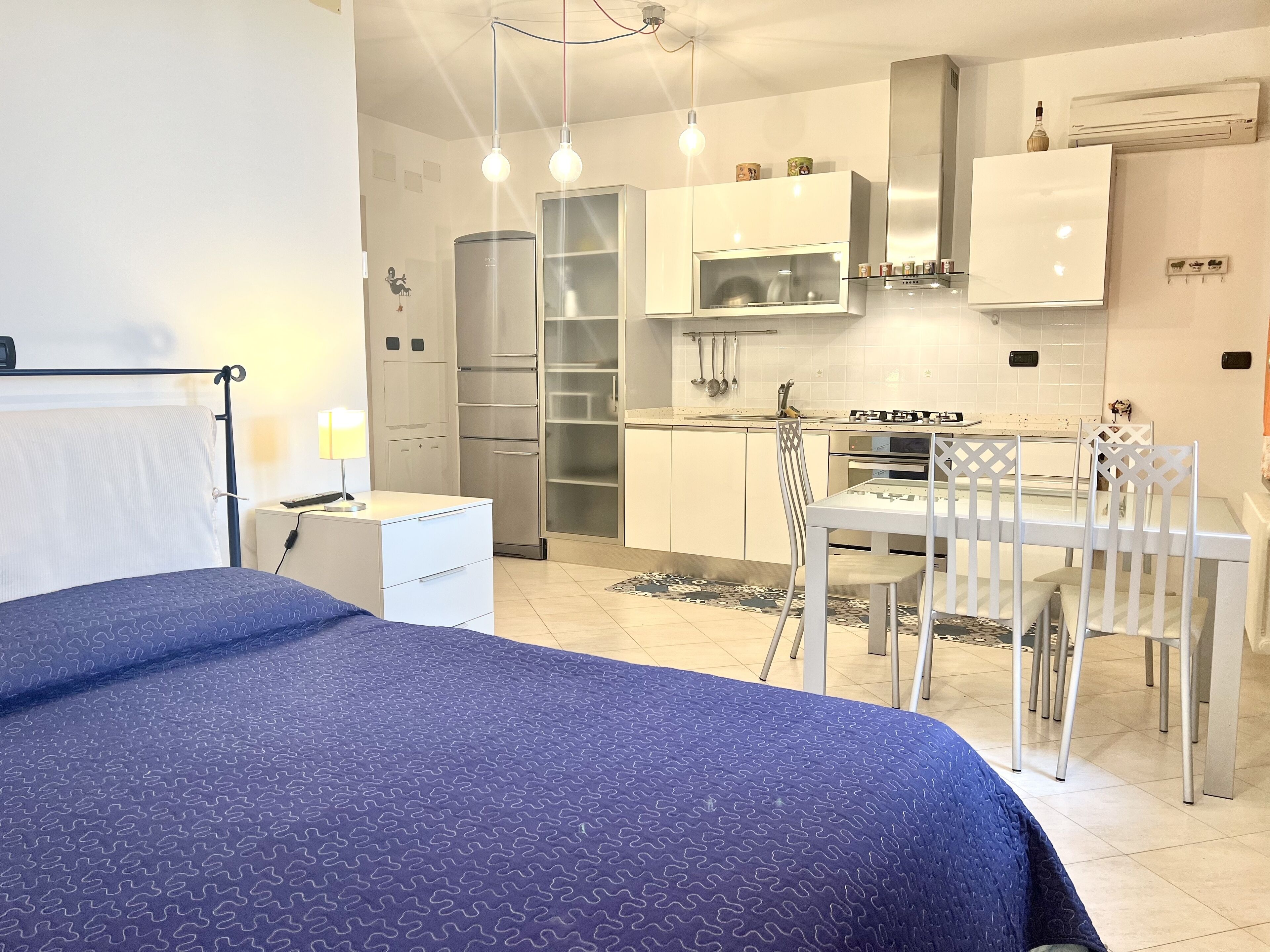 A modern bedroom with a bed, bedside table, and a desk with a lamp.