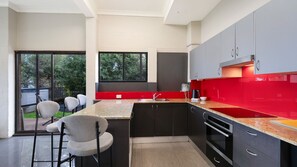 A modern kitchen with a red backsplash, black cabinets, and a built-in oven.