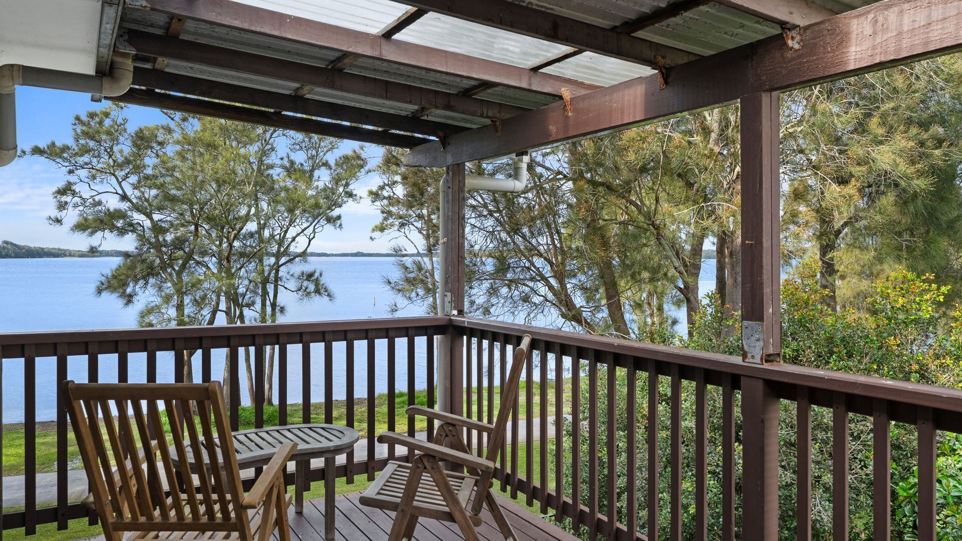 A wooden deck with a view of a lake, surrounded by trees.