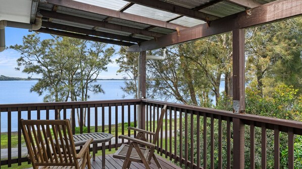 A wooden deck with a view of a lake, surrounded by trees.