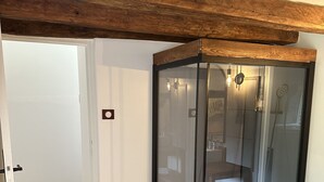 A room with a glass-enclosed shower, wooden flooring, and a white door. - Domaine de Couilleuse (Saint-Laurent-Nouan)