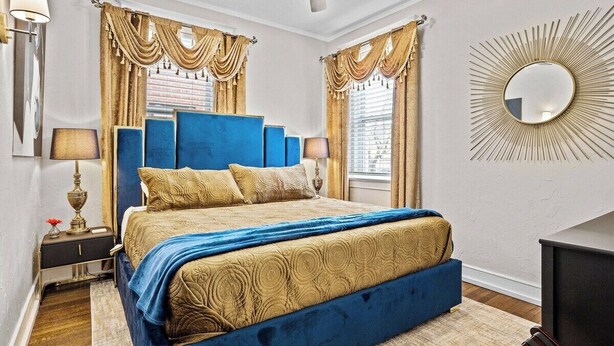 Une chambre à coucher avec un grand lit, deux tables de chevet, un ventilateur de plafond et un miroir fixé au mur.
