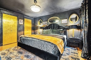 Ein Schlafzimmer mit einem Bett, Nachttischen, einem Spiegel und einem Kleiderschrank.