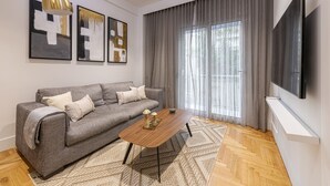 Ett modernt vardagsrum med en grå soffa, ett träbord och abstrakt konst på väggen.