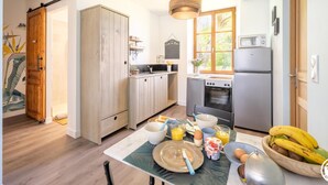 Una cocina moderna con armarios de madera, una mesa de comedor con alimentos para el desayuno y una ventana con vistas a zonas verdes.