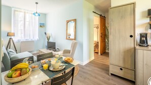 A modern kitchen with a dining area, wooden cabinets, and a view into the living room. - Charming apartment with river view, WiFi and parking (Bonnières)