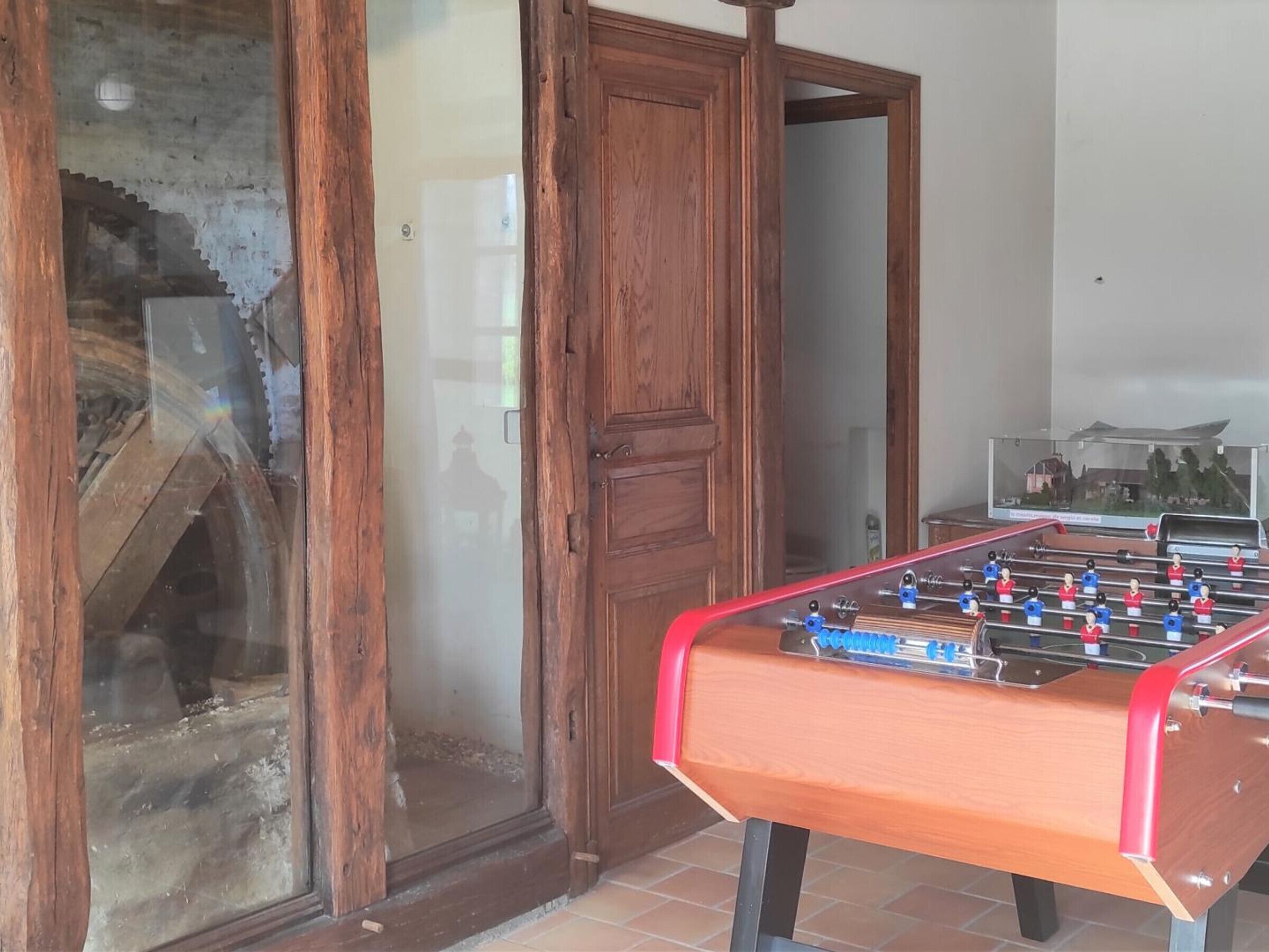 A wooden door, a glass door, and a foosball table in a room.