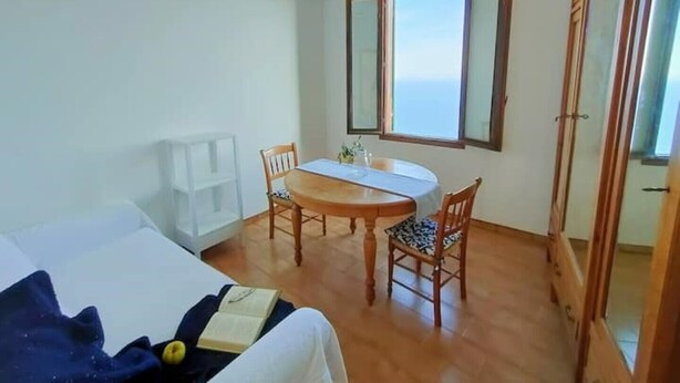A room with a bed, a dining table with chairs, a window with a view, and a wardrobe. - Bright apartment by the sea (Grimaldi)