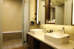 A modern bathroom with two sinks, a shower, and a large mirror.