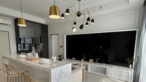 A modern kitchen with a marble island, pendant lights, and a large TV. - NOVO Serviced Suites by Widebed (Kuala Lumpur)