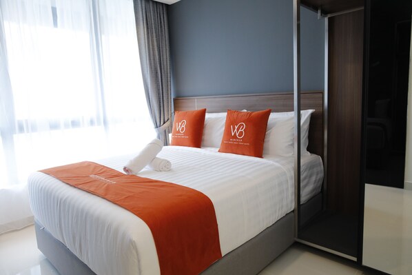 Une chambre d’hôtel moderne, avec un lit bien fait, un grand miroir et une vue sur l’extérieur.