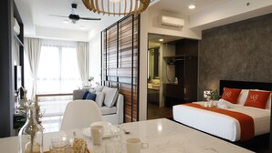 A modern hotel room with a large bed, a dining table set with glasses and plates, a sofa, and a view of the city. - NOVO Serviced Suites by Widebed (Kuala Lumpur)