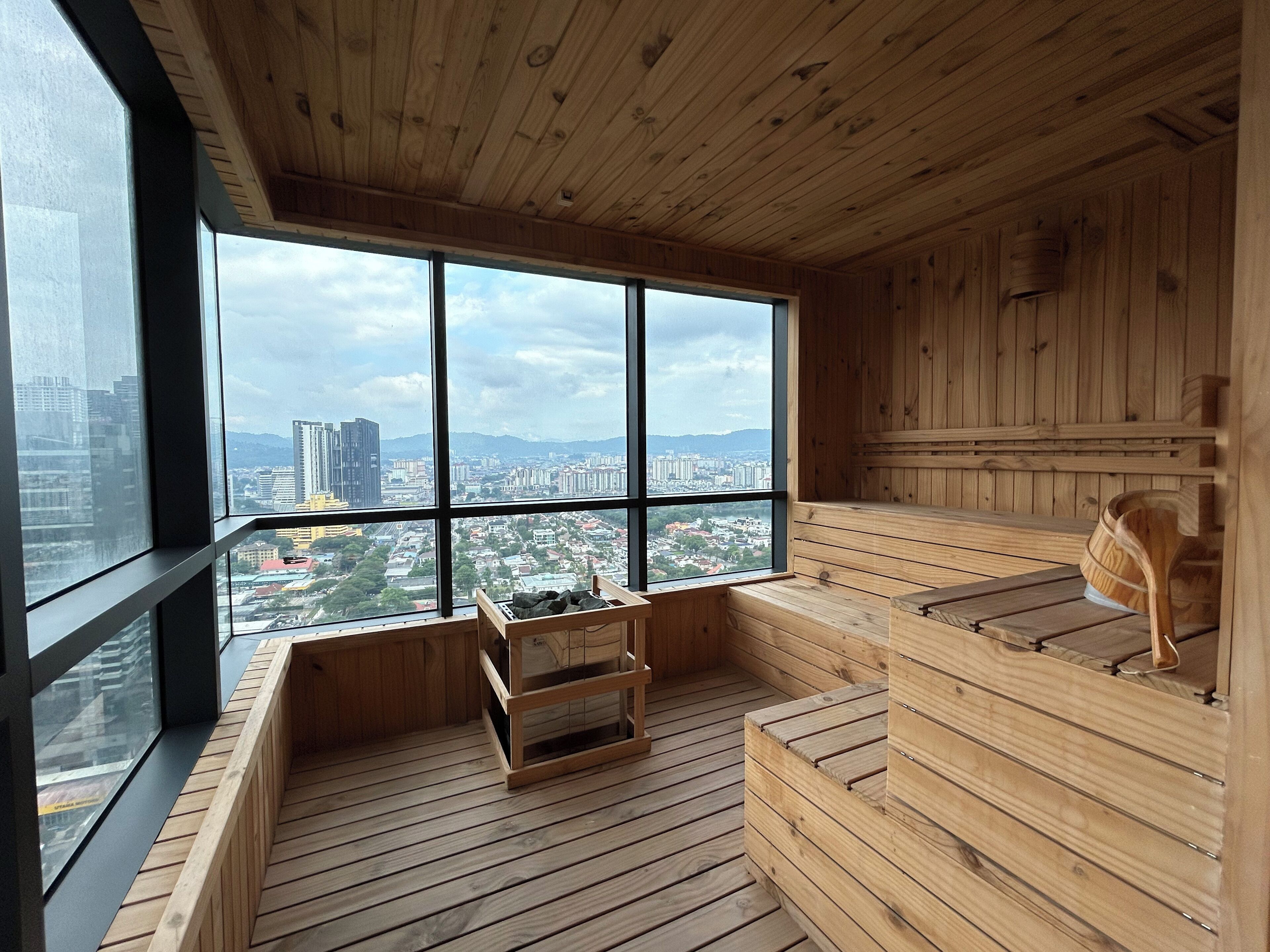 Un sauna en bois doté de grandes fenêtres offrant une vue sur la ville.