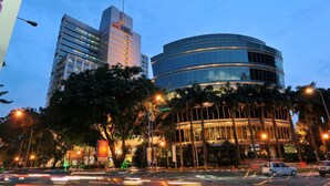 A modern building with a curved glass facade and a rectangular structure with a lion emblem. - NOVO Serviced Suites by Widebed (Kuala Lumpur)