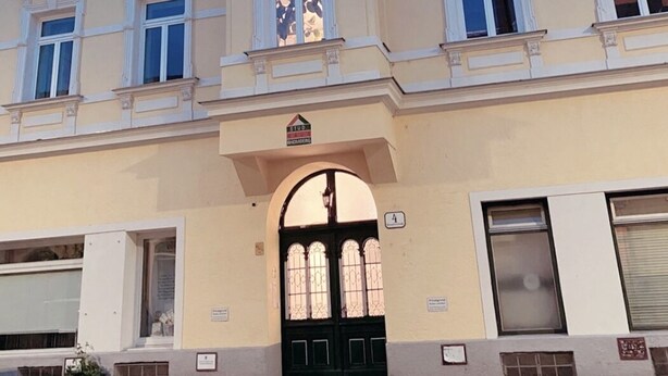 A multi-story building with a central entrance and a sign indicating it is a residential property. - Innsbruck Apartment (Innsbruck)