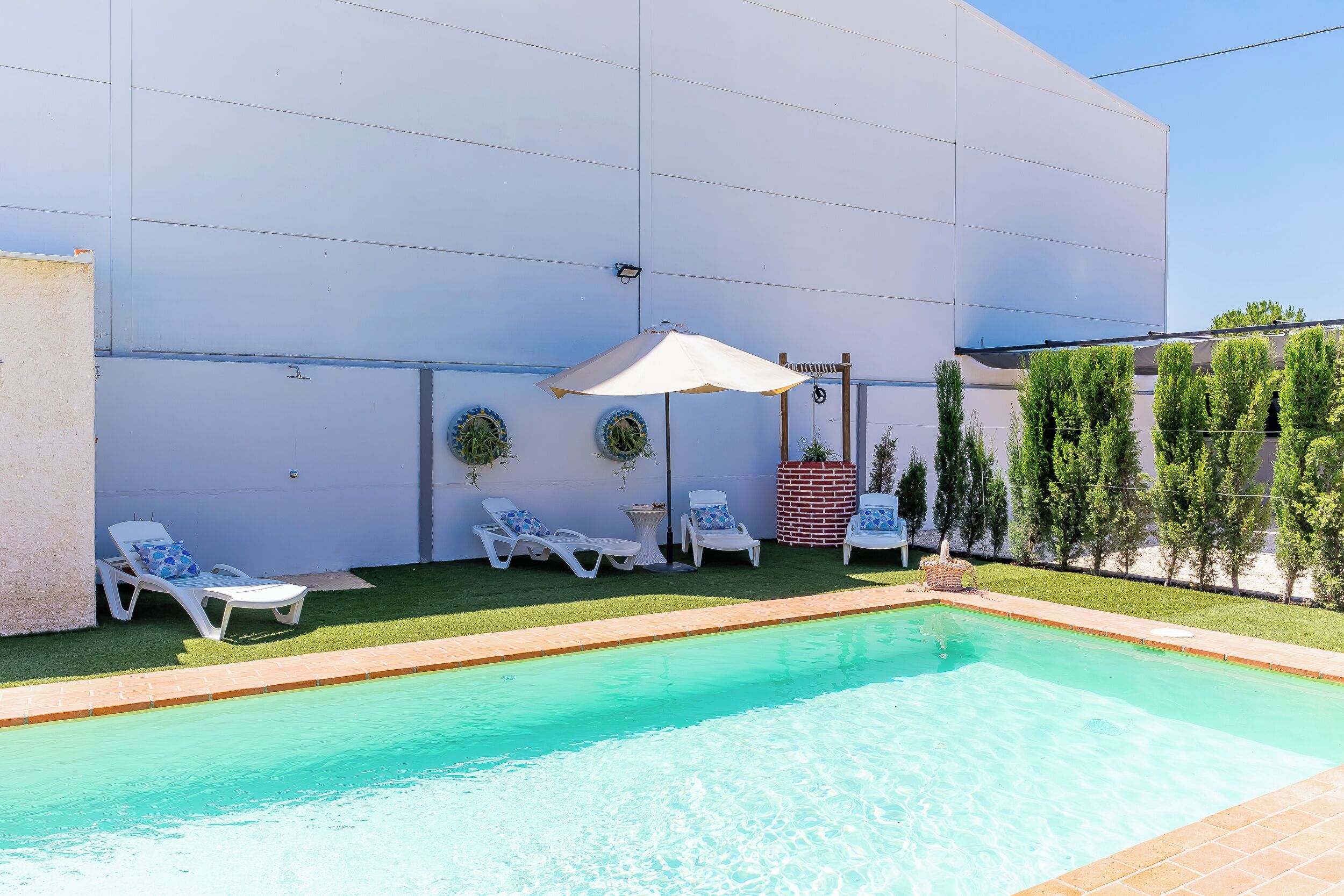 A swimming pool with lounge chairs and an umbrella.